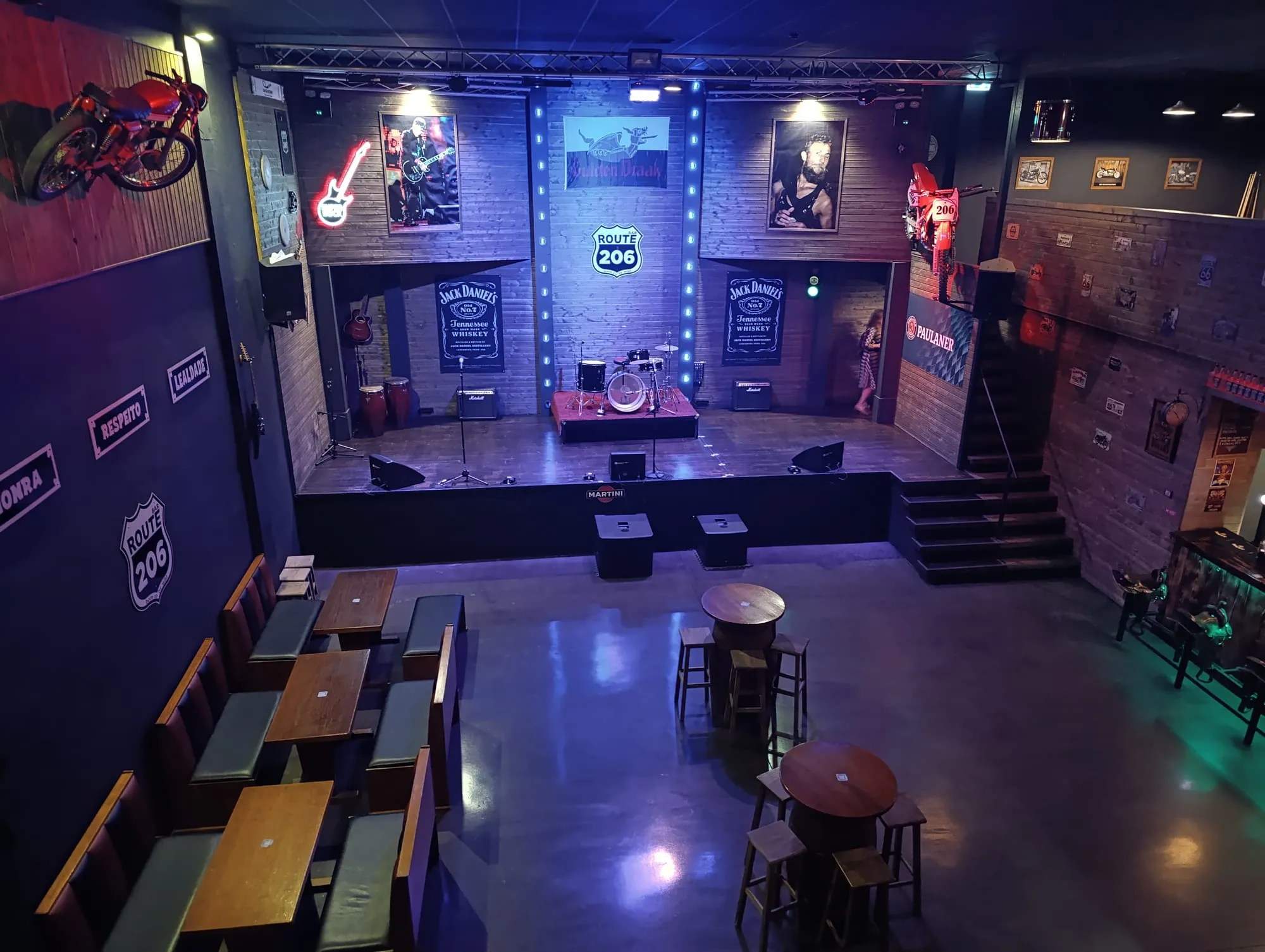 Palco do Route 206 com bateria, congas e amplificadores, iluminado a azul